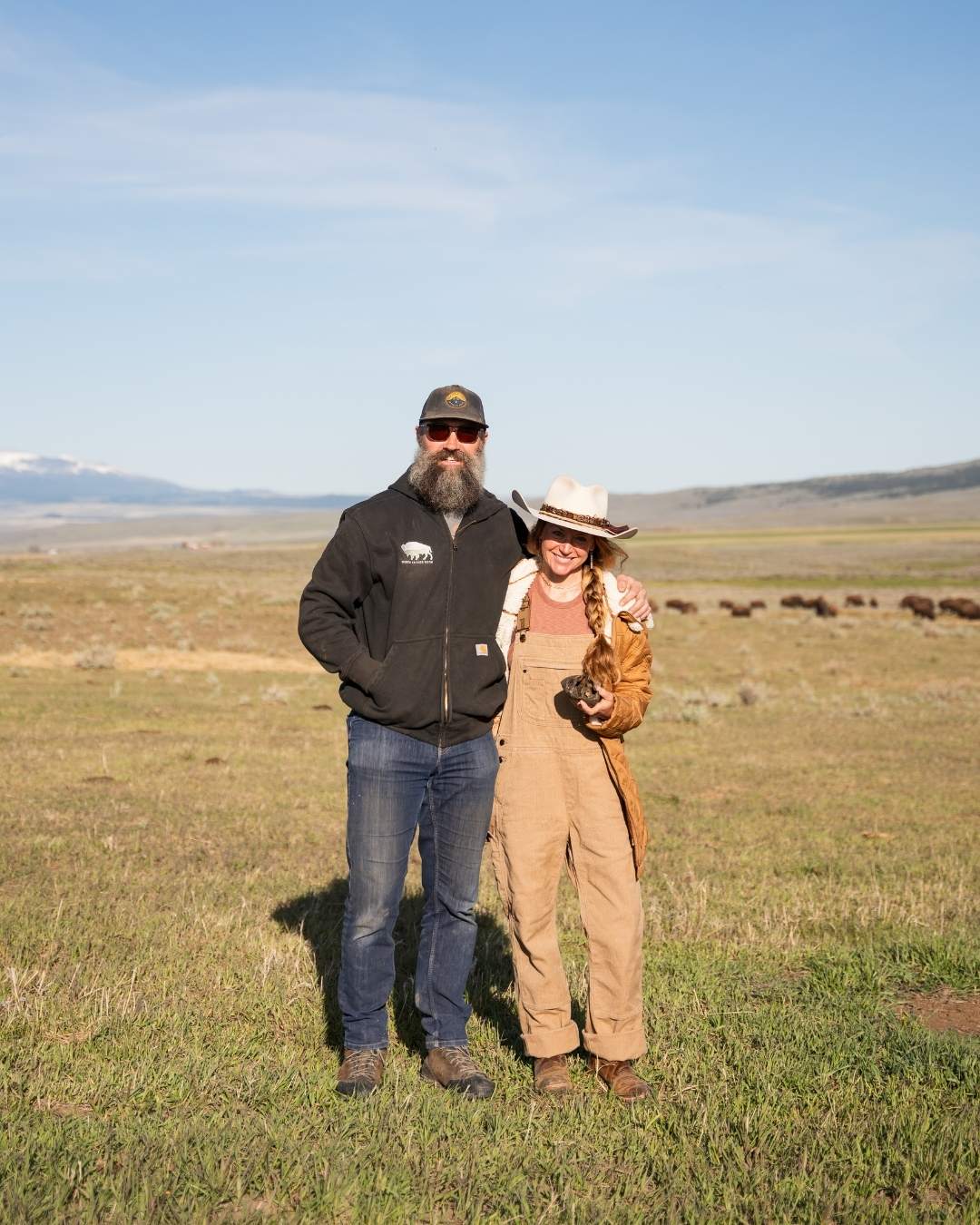 Ranchers Matt and Sarah Skoglund stand with their bison herd at North Bridger Bison in Montana’s Shields Valley, where their family-run ranch uses regenerative, holistic management to raise bison, restore grassland habitat, and produce healthy, humanely harvested meat.